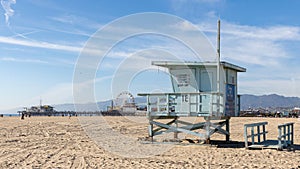 A lifeguard tower on Santa Monica beach with pier in the background located in California USA taken on February 5th 2023