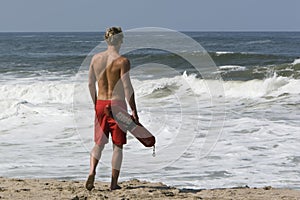 Lifeguard walking towards ocean photo