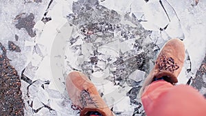 A lifeguard walks in boots on thin ice in the winter.