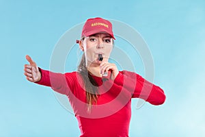 Lifeguard woman in cap on duty blowing whistle.
