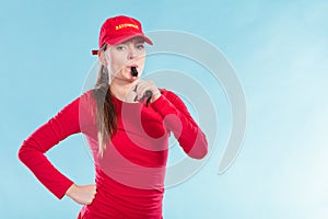 Lifeguard woman in cap on duty blowing whistle.