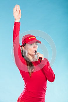 Lifeguard woman in cap on duty blowing whistle.