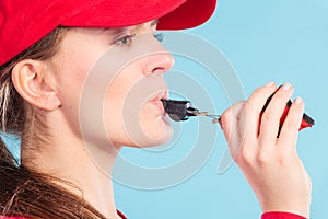 Lifeguard woman in cap on duty whistling.