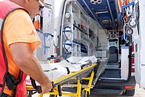Lifeguard worker working while grabbing a stretcher on an ambulance