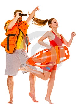 Lifeguards in life vest with rescue buoy running