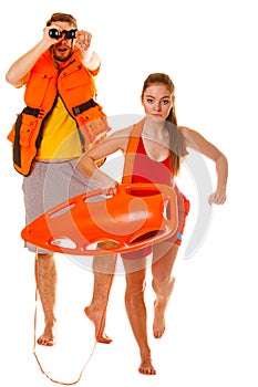 Lifeguards in life vest with rescue buoy running