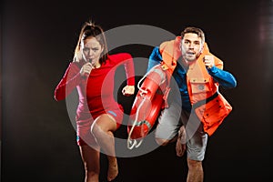 Lifeguards in life vest with ring buoy whistling.