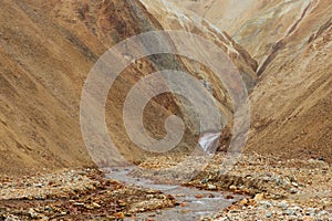 Lifeless orange and yellow hills and river running among them du