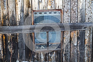 A lifeless window boarded up by a wooden board looks dejected .