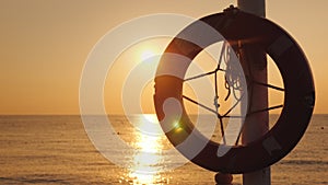 A lifeline hangs against the backdrop of the sea where the sun rises