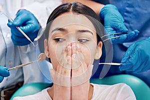 A lifelong fear being realised. a young woman covering her mouth in fear in her dentists office.