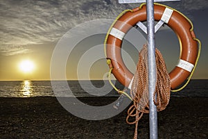Lifesaver buoyancy aid on beach at sunrise photo