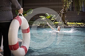 Lifesaver saving teenager girl using ringbuoy to rescue drowning in dangerous situation,asian child girl struggling in water,