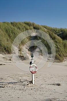 Lifesaver at station on beach with marram grass dune in background