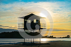 Lifesavers lookout and Leisure Island silhouetted by sunrise through cloudy sky