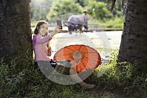 Lifestyle of Asian concept.  Young women taking selfie in the fields with the buffalo and her father. Female using a smartphone in