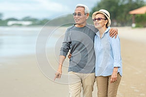 Lifestyle asian senior couple happy walking and relax on the beach.  Tourism elderly family travel leisure and activity after reti photo