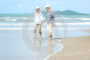 Lifestyle asian senior couple walking happy and relax on the beach.