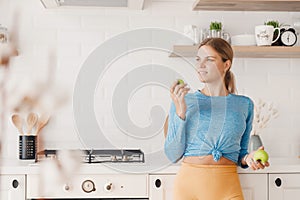 lifestyle, Beautiful Caucasian sporty woman happy smiling holding green apple in kitchen. Healthy snack for fitness girl