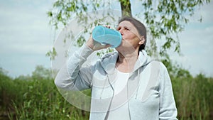 Lifestyle, beautiful elderly woman takes care of health quenches her thirst drinks clean cool water after playing sports