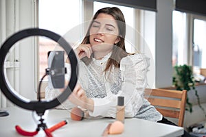 Lifestyle beauty blogger streaming online from home studio. Diverse millennial woman working as make up artist and recording video