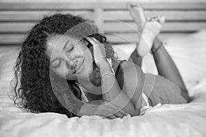Lifestyle black and white portrait of young happy and gorgeous hispanic woman posing and playful at home bedroom lying relaxe