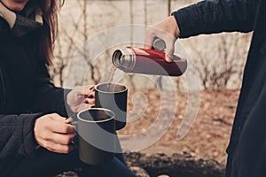 Lifestyle capture of couple drinking hot tea outdoor on cozy warm walk in forest