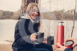 Lifestyle capture of couple drinking hot tea outdoor on cozy warm walk in forest