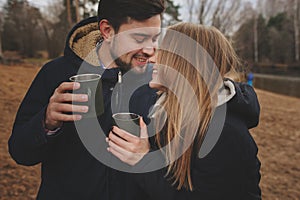 Lifestyle capture of happy couple drinking hot tea outdoor on cozy warm walk