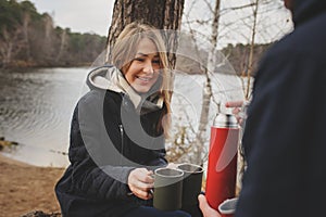 Lifestyle capture of happy couple drinking hot tea outdoor on cozy warm walk