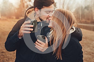 Lifestyle capture of happy couple drinking hot tea outdoor on cozy warm walk in forest