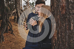 Lifestyle capture of happy couple drinking hot tea outdoor on cozy warm walk