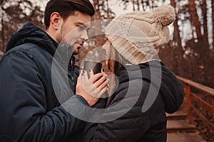 Lifestyle capture of happy couple drinking hot tea outdoor on cozy warm walk