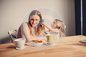 Lifestyle capture of happy mother and baby girl having breakfast at home