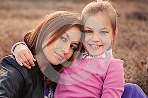 Lifestyle capture of happy mother and preteen daughter having fun outdoor. Loving family spending time together on the walk.