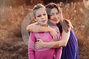 Lifestyle capture of happy mother and preteen daughter having fun outdoor. Loving family spending time together on the walk.