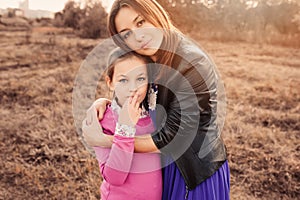 Lifestyle capture of happy mother and preteen daughter having fun outdoor. Loving family spending time together on the walk.