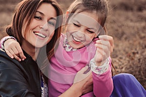 Lifestyle capture of happy mother and preteen daughter having fun outdoor. Loving family spending time together on the walk.