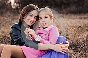 Lifestyle capture of happy mother and preteen daughter having fun outdoor. Loving family spending time together on the walk.