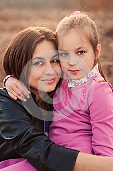 Lifestyle capture of happy mother and preteen daughter having fun outdoor. Loving family spending time together on the walk.