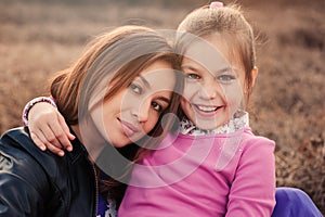 Lifestyle capture of happy mother and preteen daughter having fun outdoor. Loving family spending time together on the walk.