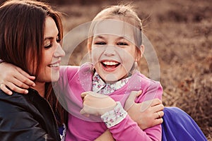 Lifestyle capture of happy mother and preteen daughter having fun outdoor. Loving family spending time together on the walk.