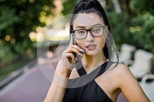 Lifestyle close up portrait of beautiful confident Asian business woman in park outdoors, wearing black dress and