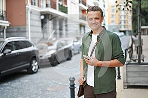 Lifestyle concept as handsome man is seen with mobile phone on charming streets of old city in Europe. urban