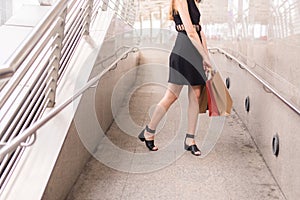 Lifestyle concept,Confident girl in blackdress smling and holding shopping bags in city