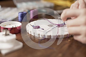 Lifestyle concept, work from home to reinvent your life: close-up of woman hands making macrame knots the fuchsia thread creating