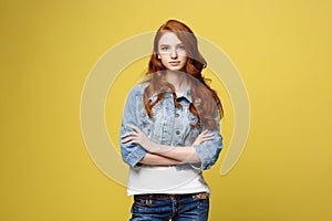 Lifestyle Concept: Young caucasian beautiful woman in denim jacket crossed arms - isolated over bright yellow backgroun