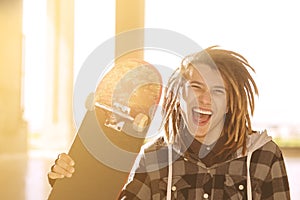 Lifestyle concept of young guy with skateboard and rasta hair w