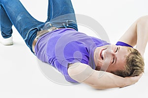 Lifestyle concept: Young Smiling Happy Caucasian Handsome Man Lying on Floor and Laughing. Casual Clothes Style.