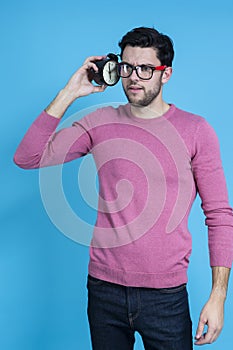 LIfestyle Concepts. Portrait of Young Caucasian Man in Glasses Gesturing With Alarm Clock And Lifted Hand